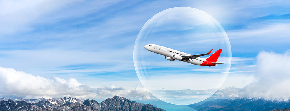 Plane surrounded by a bubble flying over mountains