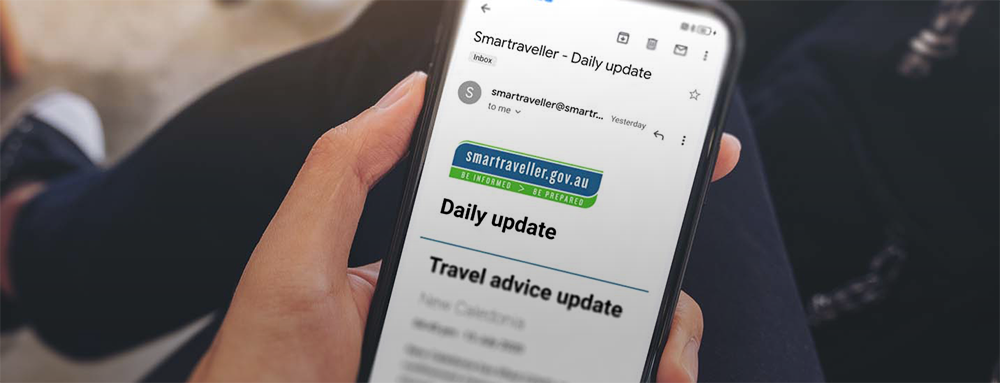 Hand holding phone showing Smartraveller subscription email