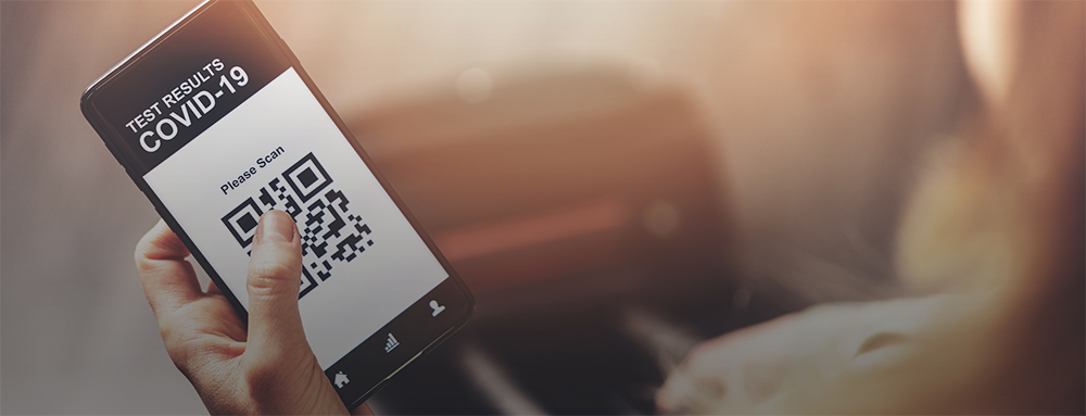 A COVID-19 test result QR code on a mobile phone screen held in a hand